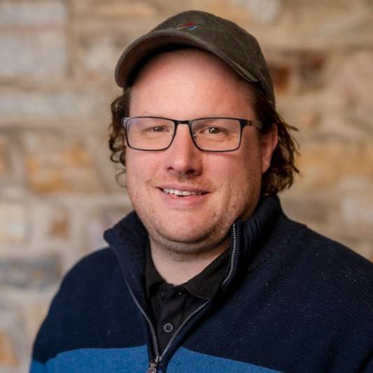 Smiling man with glasses in a baseball cap