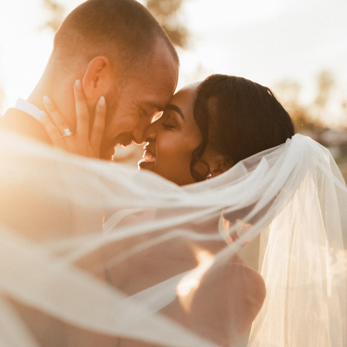 bride and groom smiling before a sunset