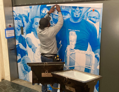 Tariq Price installing the museum’s "¡Pleibol!" exhibition, 2021