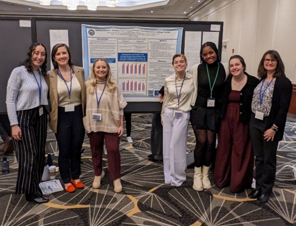 Dr. McCabe and her students gather for a photo around their reserach poster.